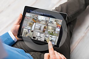 Man looking at home security cameras on tablet computer