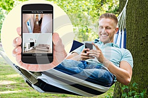 Man Looking At Home Security System On Mobilephone