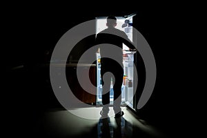 A man is looking inside an open refrigerator. Ai generated.