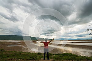 Man looking at lake view floating house boat of fishing village at sunset with cloud, rain and storm.