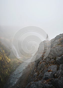 Man looking at the landscape on a mountain top on a foggy day