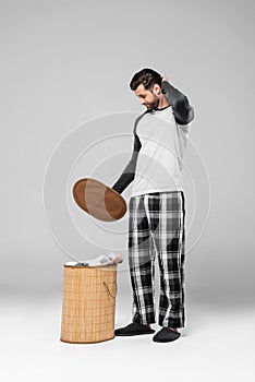 Man looking at laundry basket with dirty clothing on grey