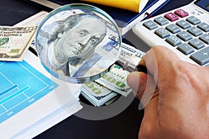 Man looking through magnifying glass on a dollar banknote. Audit and financial research.