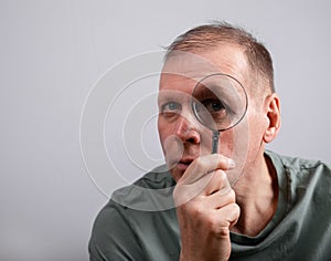 Man looking through magnifying lens