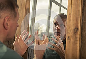 Man looking in mirror in anger and rage and shouting at him self. Psychological problem concept