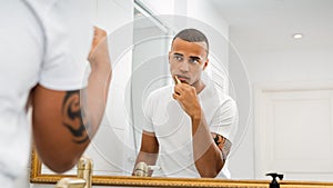 Man looking at mirror and brushing his teeth