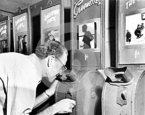 Man looking into a nickelodeon film machine