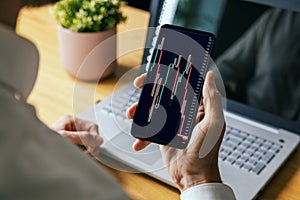 man looking at online crypto or stock market data charts on mobile phone. blockchain digital asset and ETF investment concept photo