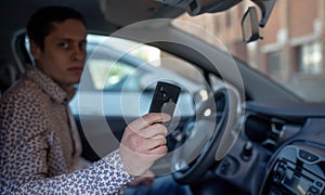 Man looking out from car window and holding a car alarm key