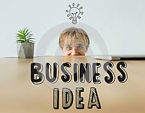 Man looking out from table and looking at camera with business idea inscription and light