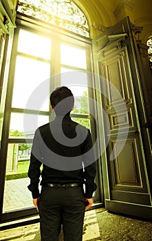 Man looking out window in golden sunlight in palace.