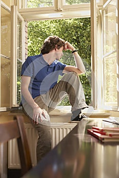 Man Looking Out Of Window Sill In Study Room