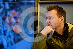 Man looking out of the window of train during travel on cogwheel railway/rack railway in Alps mountains