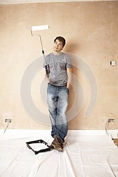 Man Looking At Paint Roller In Unrenovated House