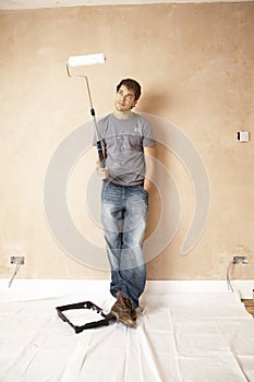 Man Looking At Paint Roller In Unrenovated House photo
