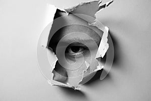 Man looking through paper. A jealous husband. Hole torn in paper with the eye of boy. Portrait of man looking through