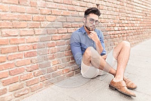 Man looking pensive while sitting on the sidewalk