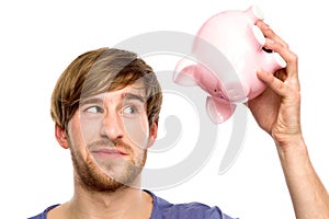 Man looking at piggy bank suspiciously