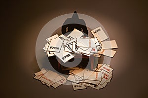 Man looking at piles of warning notices and over due letters on a table in dark background. Debt and bankruptcy concept