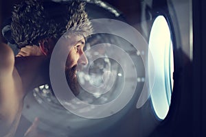 Man looking through porthole of a ship