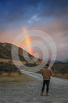 Man looking at rainbow over mountain