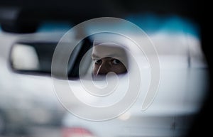 Man looking in the rear view mirror while driving