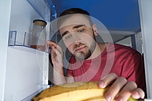 Man looking into refrigerator and choosing products