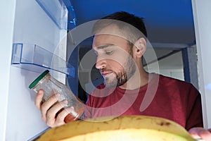 Man looking into refrigerator and choosing products