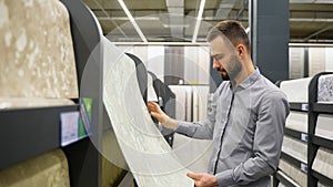 A man looking samples of designer wallpaper in household store