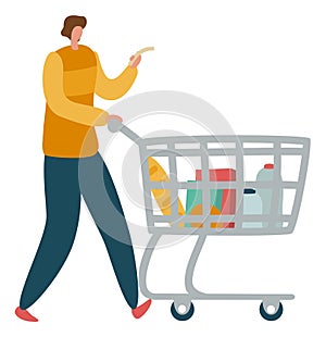 Man looking at shopping list and pushing supermarket trolley