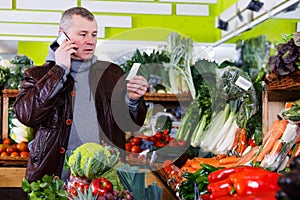 man looking at shopping list, speaking by phone