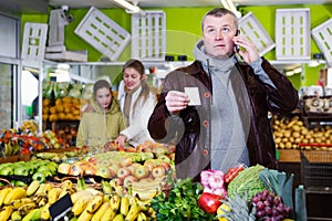 man looking at shopping list, speaking by phone
