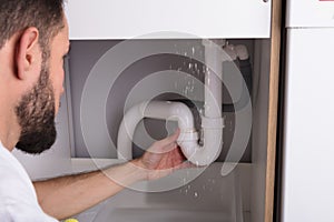 Man Looking At Sink Pipe Leakage