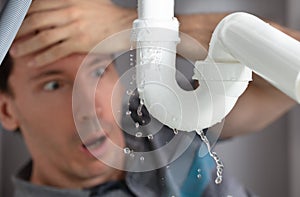 Man Looking At Sink Pipe Leakage In Kitchen photo