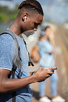 man looking at smart phone and waiting on station platform