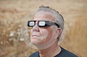 Man looking at the solar eclipse with eclipse glasses