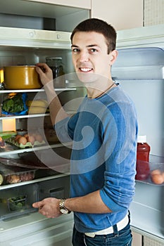 Man looking for something in pan near fridge