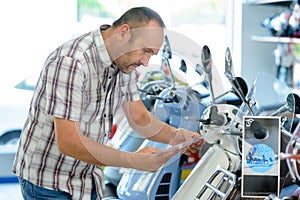 Man looking at specifications modern scooter in showroom