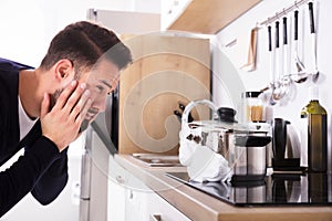 Man Looking At Spilling Out Boiled Milk From Utensil