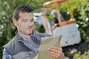 Man looking at tablet digger working in background