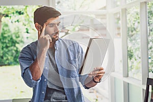 A man looking and thinking at note book