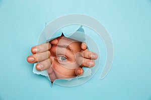 Man looking through torn blue background