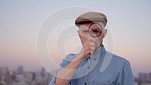 Man looking using magnifying glass outdoor with urban view