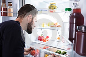 Man Looking At Vegetables In Refrigerator