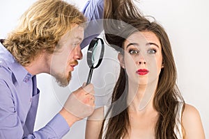 Man looking at woman hair through magnifer