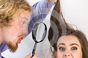 Man looking at woman hair through magnifer