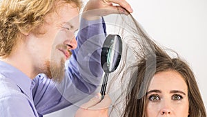 Man looking at woman hair through magnifer