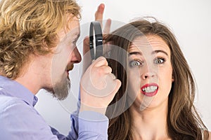 Man looking at woman hair through magnifer