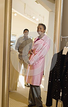 Man Looking At Woman Trying Overcoat In Store photo