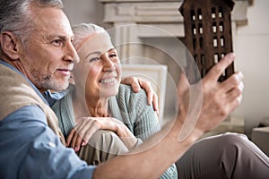 Man looking at wooden house model in hands with smiling wife